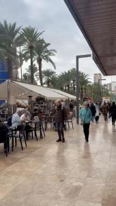 a group of people walking on a sidewalk with tables and chairs at EXPLANADA BEACH FLAT in Alicante