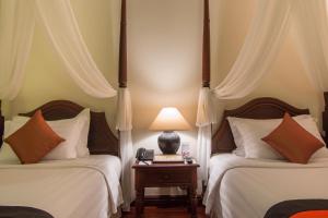 Postel nebo postele na pokoji v ubytování Angkor Palace Suite & Villa
