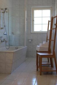 uma casa de banho com uma banheira, um chuveiro e uma cadeira. em Ferienwohnung Waxenstein em Garmisch-Partenkirchen