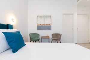 a bedroom with a white bed and two chairs at Baia Flegrea Meublè in Bacoli
