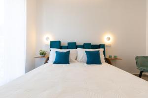a large bed with blue and white pillows on it at Baia Flegrea Meublè in Bacoli