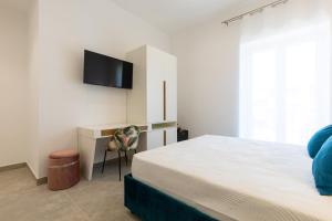 a bedroom with a bed and a desk with a television at Baia Flegrea Meublè in Bacoli