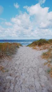 un chemin de sable menant à l'océan sur une plage dans l'établissement Ferienwohnung Kijas, à Wismar