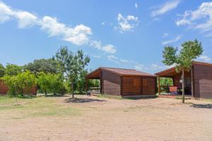 un paio di piccoli edifici in legno in un campo di Ecològic Vinyols Camp a Vinyols i els Arcs