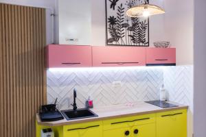 een keuken met een wastafel en roze en gele kasten bij Seek and Hide - Csilla's Tiny Hideaway in Braşov