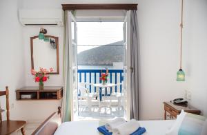 a bedroom with a door open to a balcony with a table at Adonis Hotel Naxos in Apollon