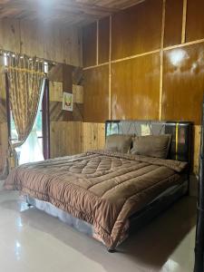 ein großes Bett in einem Schlafzimmer mit einer Holzwand in der Unterkunft Ulina Homestay VIP Berastagi in Berastagi