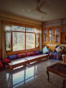 ein Wohnzimmer mit einem Sofa und einem großen Fenster in der Unterkunft MyTribe Homestay in Manali