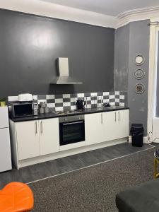a kitchen with white cabinets and a black wall at Black Ocean Holiday Apartments in Blackpool