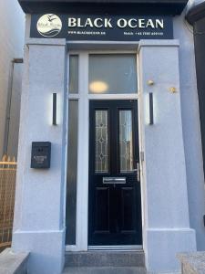 a black door on a white building with a sign at Black Ocean Holiday Apartments in Blackpool