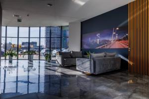 ein Wohnzimmer mit zwei Sofas und einem großen Bildschirm in der Unterkunft Panorama Capital Tito - 16 piętro in Rzeszów