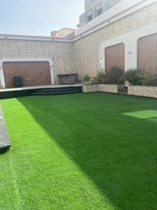 a yard with green grass and a building at black tiger villa in ‘Ezbet `Abd el-Ḥamîd