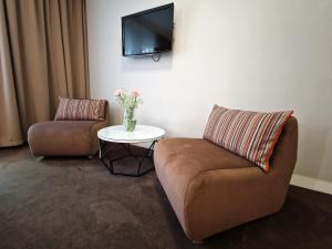 sala de estar con 2 sillas y TV en la pared en Platinum Apartments Aparthotel, en Poznan