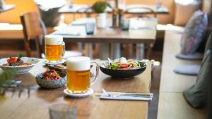 una mesa con dos vasos de cerveza y un tazón de comida en Hotel Soyka en Špindlerův Mlýn