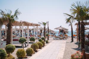 a beach with palm trees and umbrellas and the ocean at MCM Camping in Ulcinj