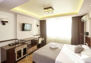 a hotel room with a bed and a flat screen tv at Black Sea Guest House in Adler