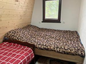 Ce lit se trouve dans un dortoir doté d'une fenêtre. dans l'établissement Vikendice Jahorinska Dvorišta, à Pale