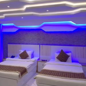 SEASHELLINN HOTEL في كراتشي: سريرين في غرفة ذات إضاءة أرجوانية