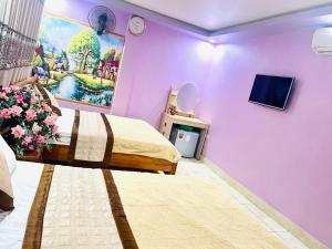 a bedroom with purple walls and a bed and a tv at Pink Boutique Inn - Hotel Elite in Cat Ba