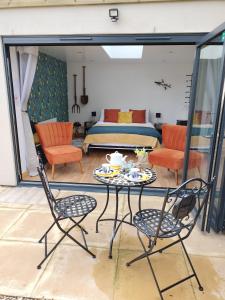 Private Garden Room - Rural Village في ستامفورد: غرفة مع طاولة وكراسي وسرير