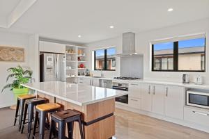 a kitchen with white cabinets and a large island with bar stools at Hunter 3 Bedroom Apartment C in Lake Tekapo