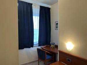Habitación con escritorio y ventana con cortinas azules. en 1000 Miglia, en Monteroni dʼArbia