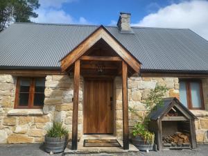 a stone cottage with a wooden door and a slate roof at The Cottage Burradoo in Burradoo