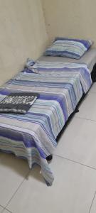 a bed with a striped blanket sitting on the floor at casa nova com ar condicionado in Pirapora