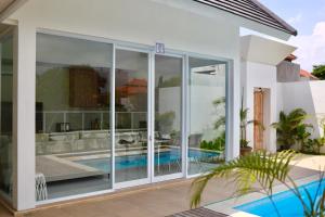 a house with a swimming pool and glass walls at White Villa 212 in Canggu