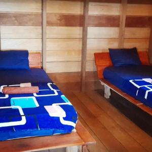 Nyang Ebay Surf Camp siberut front E-Bay,Beng-Bengs,Pitstops,Bank Vaults,Nipussi في Masokut: سريرين في غرفة بجدران خشبية