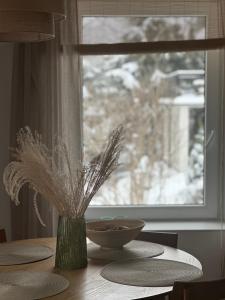 una mesa con un jarrón en una mesa con una ventana en W deSki dom apartamenty, en Krzyżowa