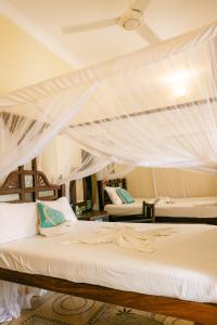 a bedroom with two beds with mosquito nets at Caravan Serai Amour in Stone Town