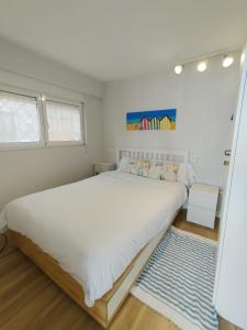 Dormitorio blanco con cama grande y alfombra azul en Rincón de Mar - En Playa Estaño, en Gijón