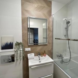 a white bathroom with a sink and a mirror at TS New Town Top Apartment in Szczecin