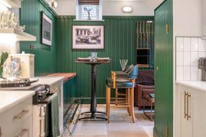 a kitchen with green walls and a table and chairs at Luxury Mews House in Harrogate in Harrogate