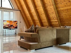 a living room with a couch and a tv at Qafqaz Mountain Chalet in Gabala
