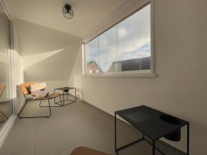 ein weißes Zimmer mit einem Tisch und einem Fenster in der Unterkunft Roof Lounge in Südbrookmerland