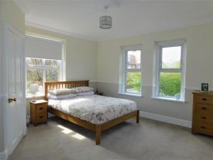 a bedroom with a bed and two windows at Corner House in Sheringham