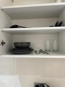 a shelf with plates and bowls and glasses on it at Modern 1BD apartment in London