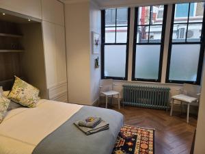 a bedroom with a bed and some large windows at Boutique Linden Gardens 1st floor and loft apartments in London