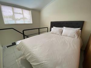 een slaapkamer met een bed met witte lakens en een raam bij Unit 76 Melville Mews in Johannesburg