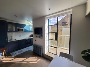 a kitchen with blue cabinets and a large window at Boutique Linden Gardens 1st floor and loft apartments in London