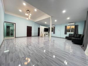 a large living room with blue walls and a wooden floor at หลัง 1 เฌอเฌอ การ์เด้น เฮาส์ ที่พักคำชะโนด in Ban Nong Sawang