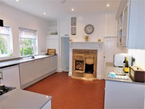 a kitchen with a fireplace with a clock on the wall at Clarendon in Sheringham