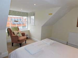 a bedroom with a bed and a chair and a window at Clarendon in Sheringham