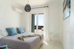 a bedroom with a bed and a table and a window at Villa Crystal by Mykonos Mood in Fanari