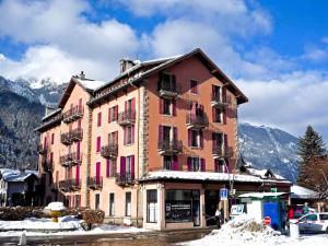 een groot gebouw met roze deuren en ramen in de sneeuw bij Appartement Chamonix Centre Vue MontBlanc in Chamonix-Mont-Blanc