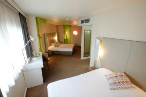 ロワシー・アン・フランスにあるホテル カンパニール ロワシーのベッド2台付きの小さな部屋とベッドルーム1室があります。