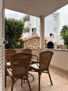 a patio with three chairs and a pizza oven at Apartmani Samec in Novalja