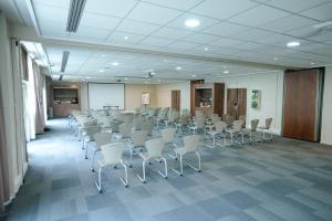 uma sala de conferências com cadeiras e um ecrã numa sala em Campanile Paris CDG Airport Villepinte em Roissy